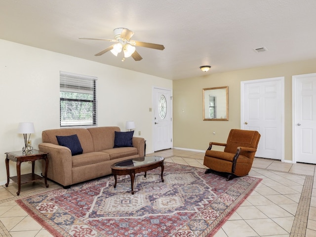 living room featuring ceiling fan, light tile patterned floors, and a textured ceiling