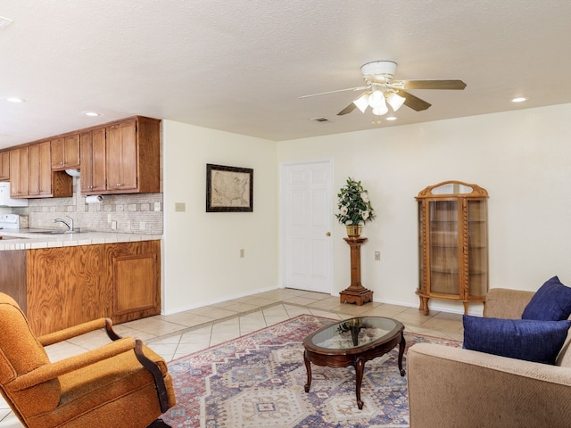 living room with ceiling fan, light tile patterned flooring, sink, and a textured ceiling