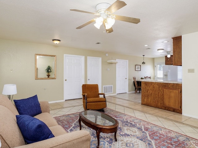 living room with ceiling fan, light tile patterned flooring, and a textured ceiling