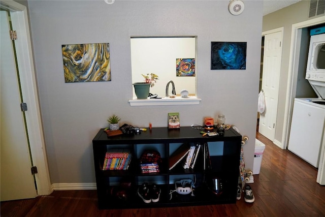 room details with wood-type flooring and stacked washer / dryer