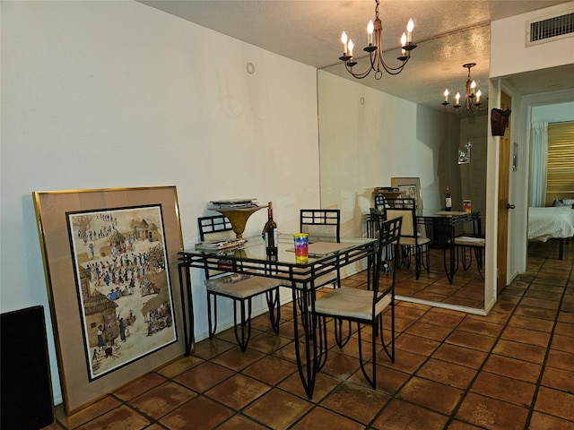 dining room featuring a notable chandelier, dark tile patterned flooring, and a textured ceiling