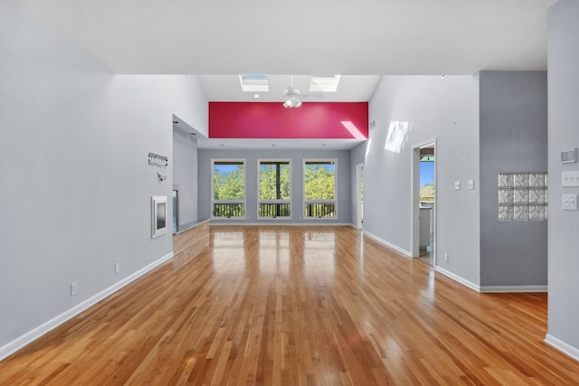 unfurnished living room featuring light wood-type flooring and a skylight