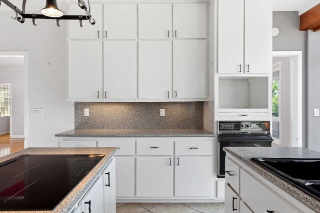 kitchen with backsplash, black appliances, white cabinets, and light tile patterned flooring