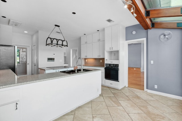 kitchen featuring sink, oven, pendant lighting, white cabinets, and stainless steel refrigerator