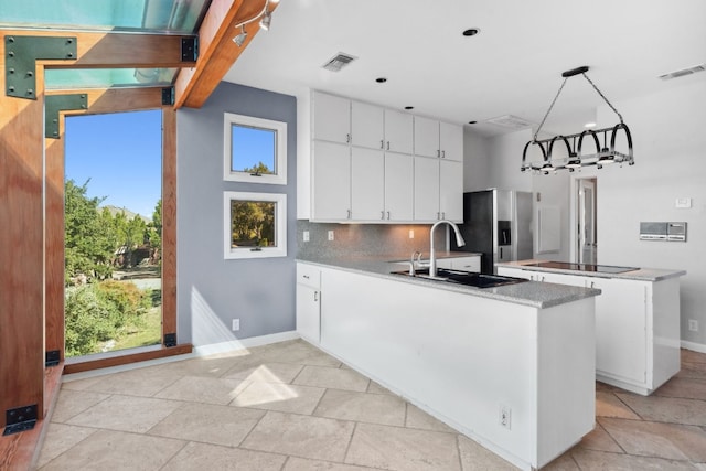 kitchen with white cabinets, decorative light fixtures, decorative backsplash, stainless steel fridge, and sink