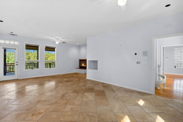 unfurnished living room with a multi sided fireplace and ceiling fan