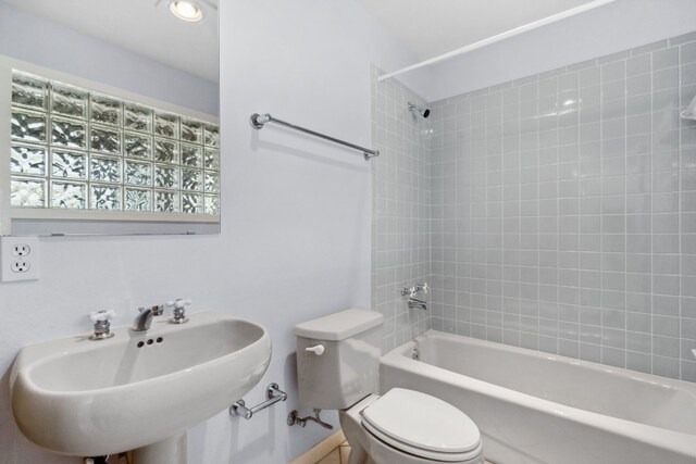 full bathroom featuring tiled shower / bath combo, sink, and toilet