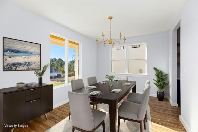 dining area with light hardwood / wood-style flooring and a notable chandelier