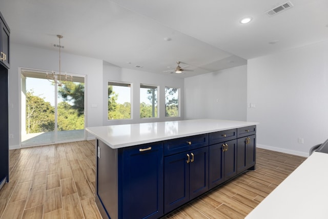 kitchen featuring pendant lighting, a kitchen island, light wood-type flooring, and blue cabinetry