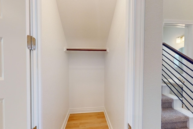 spacious closet with light wood-type flooring and vaulted ceiling