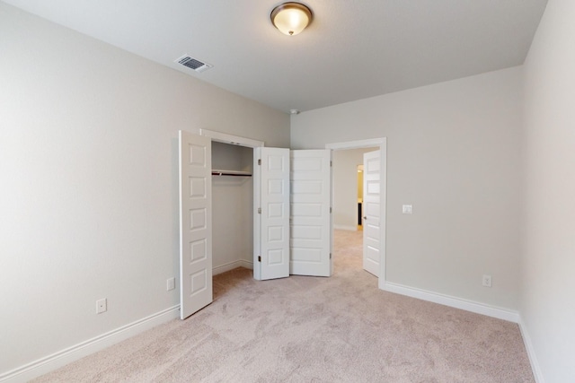 unfurnished bedroom with light carpet and a closet