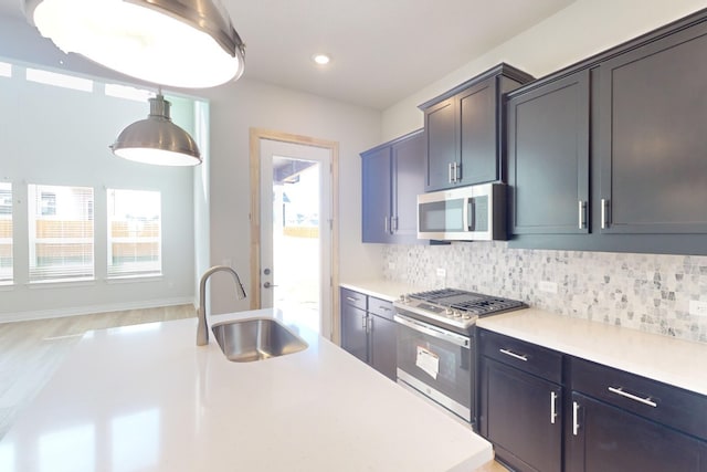 kitchen featuring tasteful backsplash, sink, stainless steel appliances, and decorative light fixtures