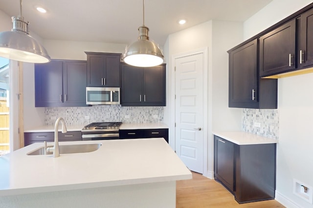 kitchen featuring backsplash, hanging light fixtures, sink, and appliances with stainless steel finishes