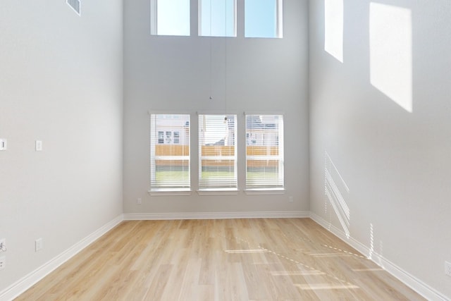 spare room featuring a high ceiling and light wood-type flooring