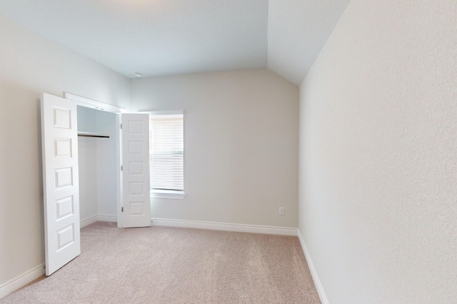 unfurnished bedroom featuring a closet, light colored carpet, and vaulted ceiling