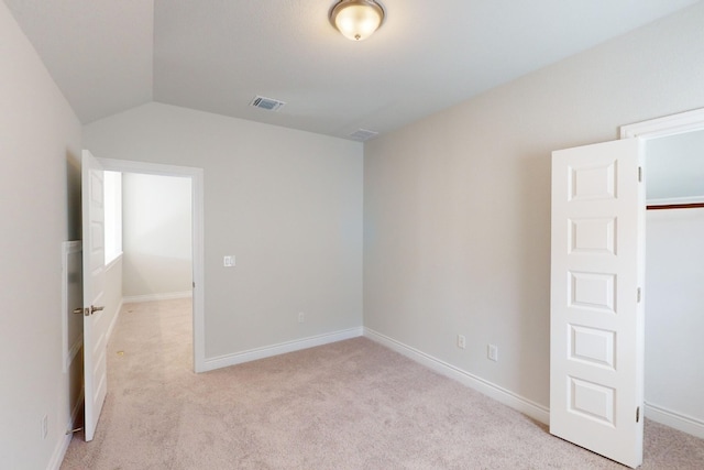 spare room with light colored carpet and vaulted ceiling