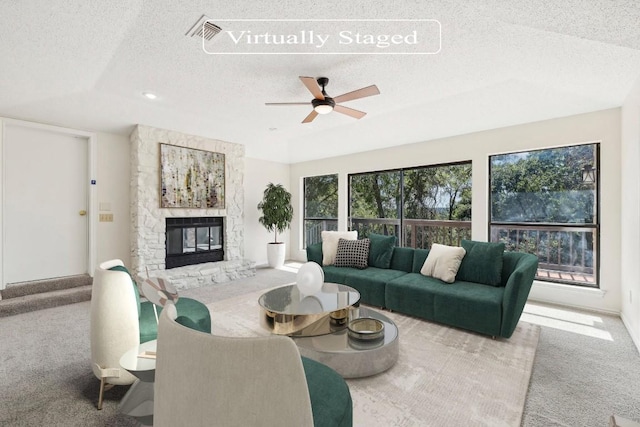 carpeted living room with a fireplace, ceiling fan, and a textured ceiling