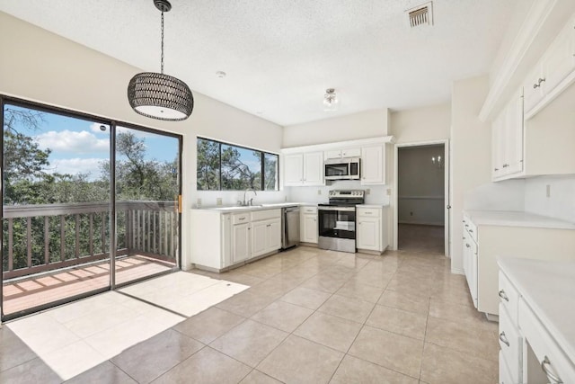 kitchen with pendant lighting, white cabinetry, stainless steel appliances, and a wealth of natural light