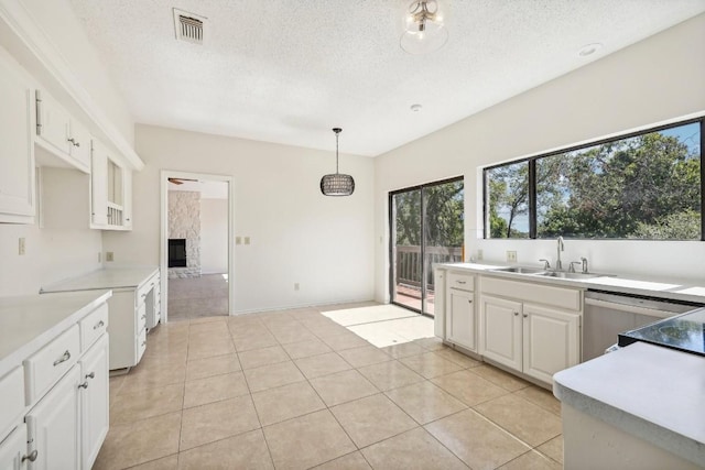 kitchen featuring dishwasher, sink, hanging light fixtures, light tile patterned floors, and white cabinetry