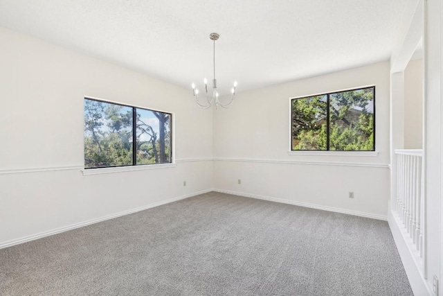 spare room with carpet flooring and a notable chandelier