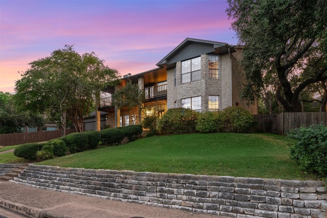 view of front of home featuring a balcony and a yard