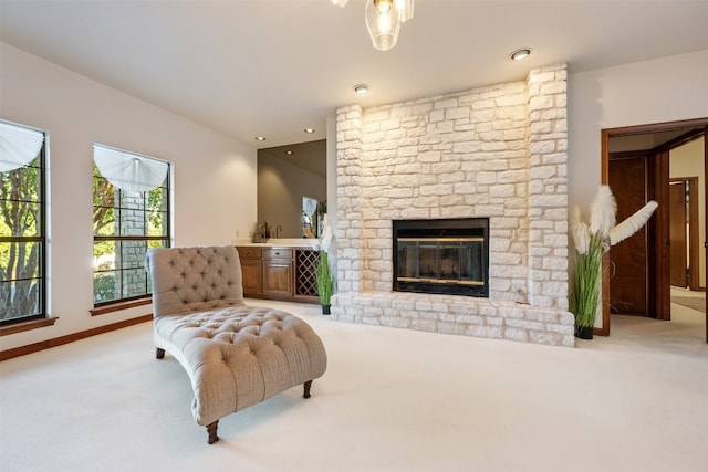 carpeted living room with a stone fireplace