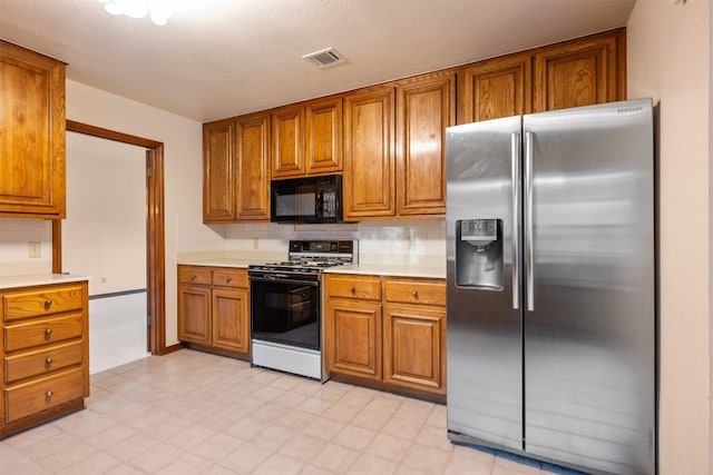 kitchen with stainless steel refrigerator with ice dispenser, white gas stove, a textured ceiling, and tasteful backsplash