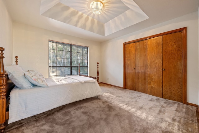 bedroom featuring a tray ceiling, a closet, and carpet floors