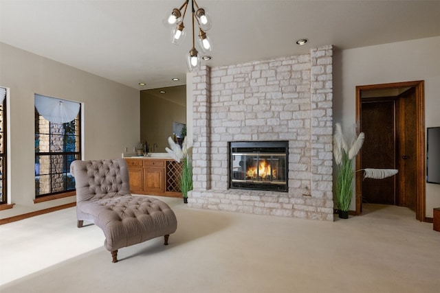 sitting room featuring light carpet, a brick fireplace, and a chandelier