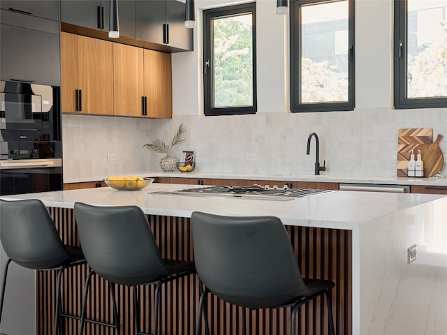 kitchen with a kitchen breakfast bar, light stone counters, tasteful backsplash, and appliances with stainless steel finishes