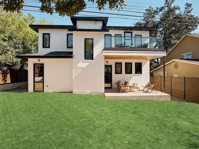 rear view of house with a balcony, a yard, and a patio