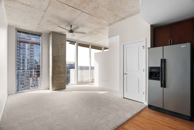 carpeted spare room featuring expansive windows and ceiling fan