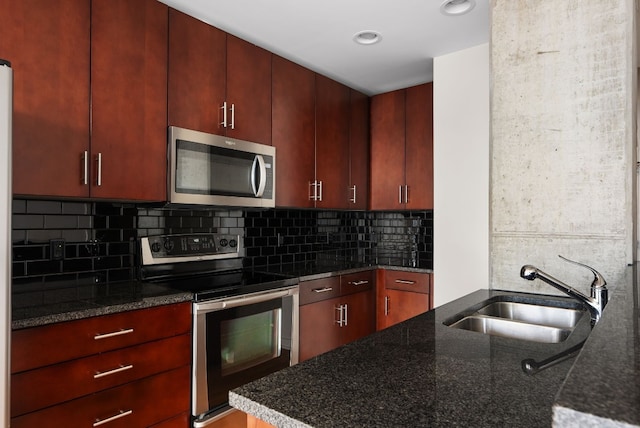 kitchen with tasteful backsplash, stainless steel appliances, sink, and dark stone countertops