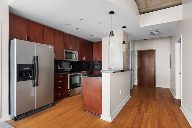 kitchen with stainless steel appliances, decorative light fixtures, light hardwood / wood-style flooring, and backsplash