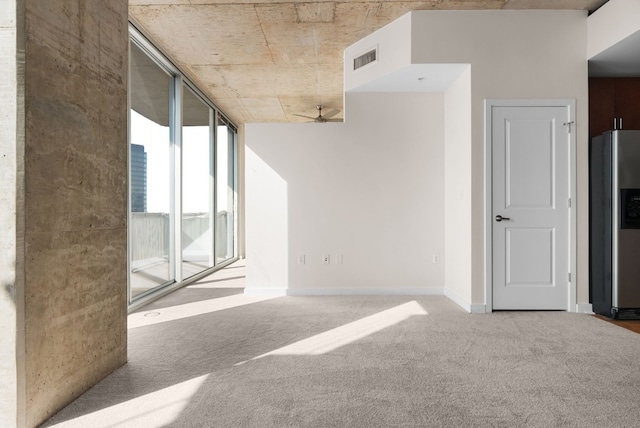 spare room with floor to ceiling windows, carpet floors, and ceiling fan