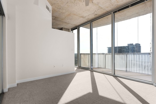 carpeted spare room featuring floor to ceiling windows and ceiling fan