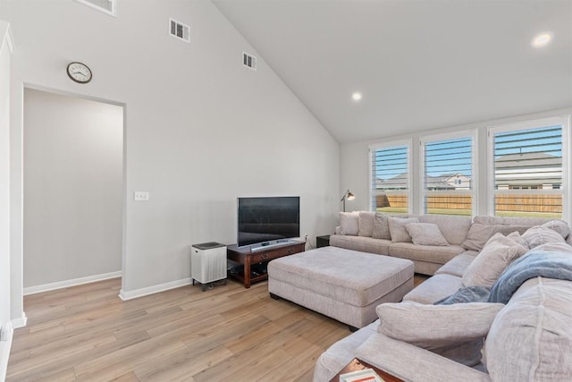 living room with light wood-type flooring and high vaulted ceiling