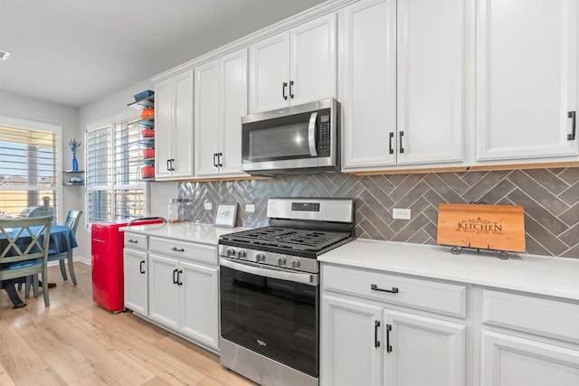 13104 Cerro Castellan Trce, Manor, TX 78653 - kitchen featuring stainless steel appliances, light countertops, decorative backsplash, white cabinetry, and light wood-type flooring