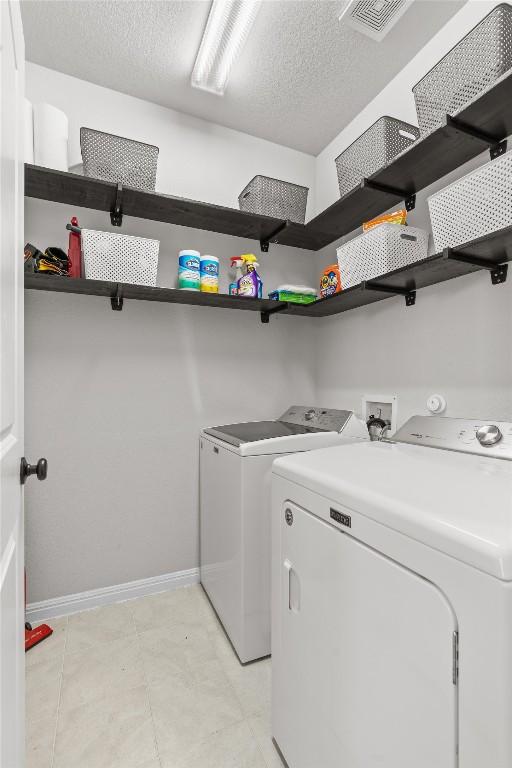 laundry area with separate washer and dryer and a textured ceiling