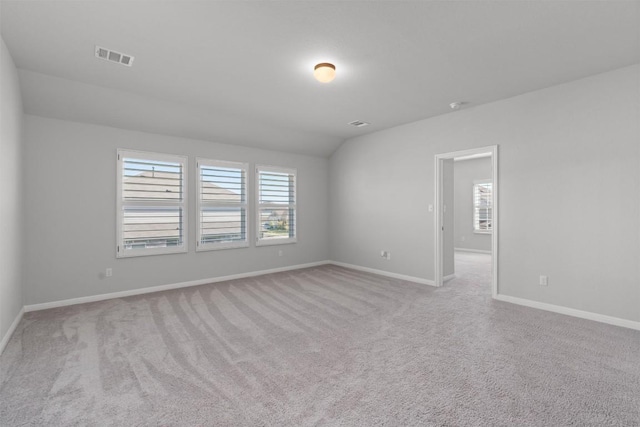 carpeted empty room with vaulted ceiling