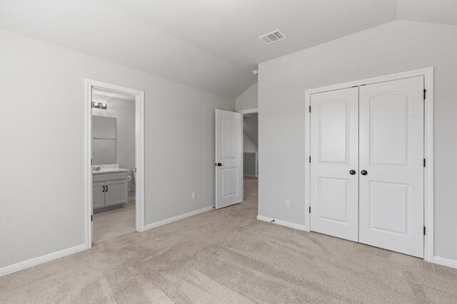 unfurnished bedroom featuring light colored carpet, vaulted ceiling, and a closet