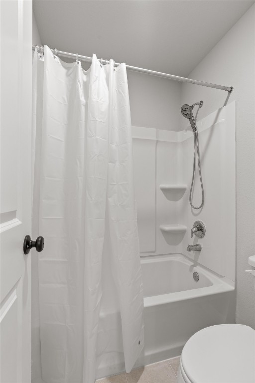 bathroom featuring tile patterned flooring, shower / tub combo, and toilet