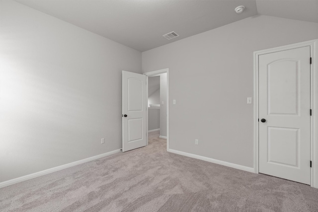 unfurnished bedroom featuring light carpet and vaulted ceiling