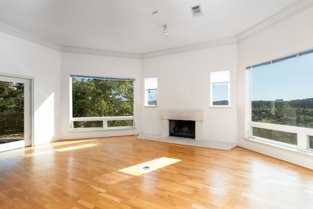 unfurnished living room featuring crown molding, plenty of natural light, light wood-style flooring, and a premium fireplace