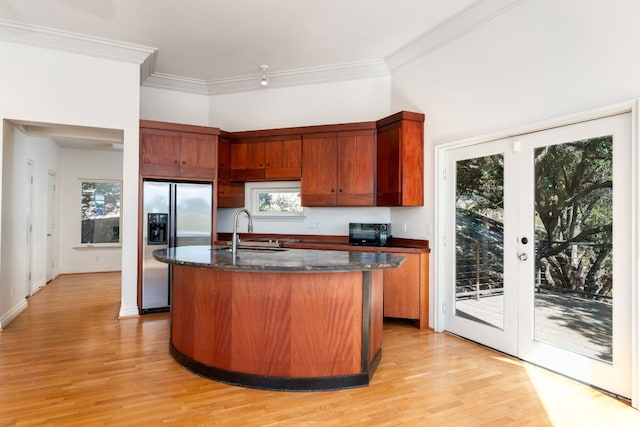 kitchen with french doors, stainless steel refrigerator with ice dispenser, ornamental molding, a sink, and an island with sink