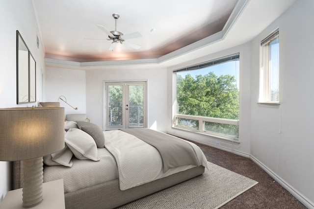 bedroom featuring baseboards, ceiling fan, a tray ceiling, french doors, and dark carpet