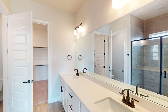 bathroom with tile patterned flooring, vanity, toilet, and a shower with shower door