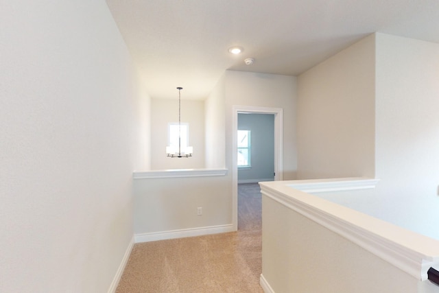 corridor featuring a chandelier and light colored carpet