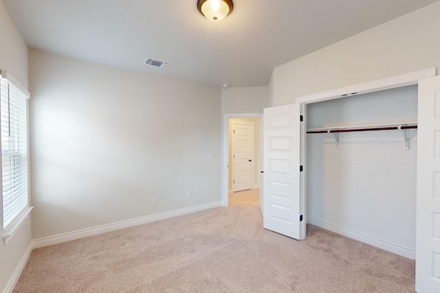 unfurnished bedroom featuring light colored carpet and a closet