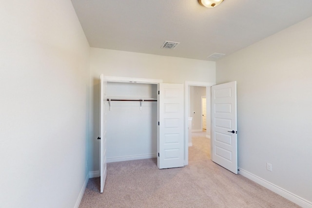 unfurnished bedroom with light carpet and a closet